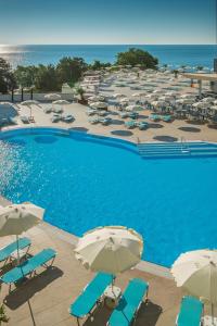 a swimming pool with umbrellas and chairs and the ocean at Astoria Hotel All Inclusive & Private Beach in Golden Sands