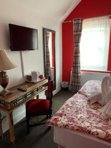 a bedroom with a bed and a desk with a television at Heathrow Stay in Hounslow