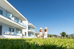 two girls standing in the grass in front of a building at Notia Luxury Living in Porto Koufo
