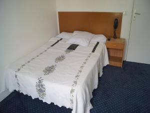 a bedroom with a white bed with a wooden headboard at Hôtel Moderne in Maisons-Alfort