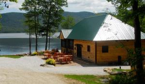 a wooden cabin with tables and chairs next to a lake at The Mountain Top Inn & Resort in Chittenden
