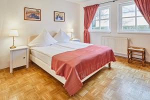 um quarto com uma cama branca e um cobertor vermelho em Gutshotel Baron Knyphausen em Eltville