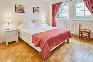 a bedroom with a white bed with a red blanket at Gutshotel Baron Knyphausen in Eltville