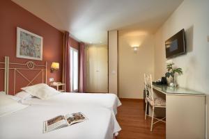 a hotel room with two beds and a television at Hotel Murillo in Seville