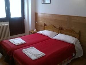 a bedroom with a red bed with two towels on it at Casa San Francesco in Bardonecchia