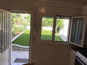 a kitchen with three windows and a view of a yard at BALATSOURAS APARTMENT in Paleros +23 photos