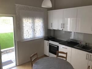 a kitchen with white cabinets and a table and chairs at BALATSOURAS APARTMENT in Paleros