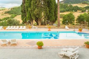una gran piscina con sillas y mesas blancas en Casale Villa Rainò, en Gangi