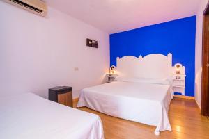 a bedroom with two beds and a blue wall at Hostal Alhambra in Zahora