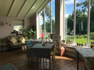 a living room with a table and chairs and windows at Netherdene Country House Bed & Breakfast in Troutbeck