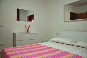 a bedroom with a bed with a colorful blanket and a mirror at Via Battisti 231 1 in Pietra Ligure