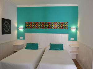 two beds in a room with a painting on the wall at Hostal Alhambra in Zahora