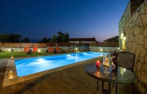 a swimming pool at night with a table next to it at Skandalis Apartments in Chorafakia