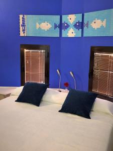 a bedroom with a bed with blue walls and two windows at Hostal Alhambra in Zahora