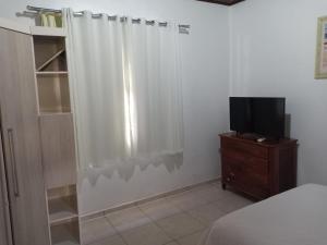 a bedroom with a white shower curtain and a tv at Casa Aconchego Fóz in Foz do Iguaçu