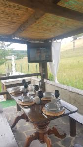 una mesa de madera con platos bajo un techo en VAL D'ORCIA DELUXE 1 ELEGANTE CASA immersa nel verde con WiFi, giardino e parcheggio, en San Giovanni dʼAsso