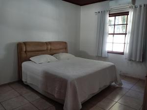 a bed in a white room with a window at Casa Aconchego Fóz in Foz do Iguaçu +24 photos