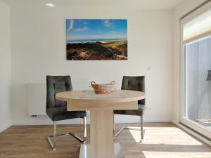 een eettafel met 2 stoelen en een foto aan de muur bij Haus Ran Ferienwohnung Ran 3 in Wittdün