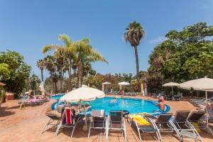 a pool with chairs and umbrellas and people swimming at Playa de las Americas Apartments in Playa de las Americas