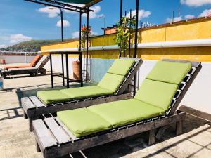 a row of green park benches in front of a building at Andaina Youth Hostel in Oaxaca City