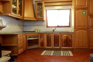 a kitchen with wooden cabinets and a window at Quinta Santo António Amares in Braga