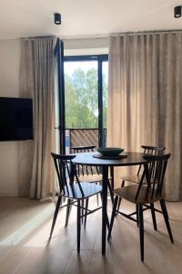 a dining room with a table and chairs and a window at Apartment KORA in Pervalka
