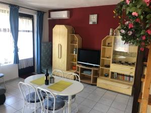 ein Wohnzimmer mit einem Tisch und einem TV in der Unterkunft Anita Apartmanház in Orfű