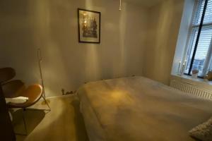 1 dormitorio con 1 cama grande y 1 silla en Cozy and silent ground floor apartment en Copenhague