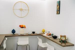 una sala da pranzo con sedie bianche e un grande orologio sul muro di B&B Stramondo a Catania Altre 25 foto