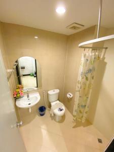 a bathroom with a toilet and a sink and a mirror at Polkadot Hostel in Phitsanulok