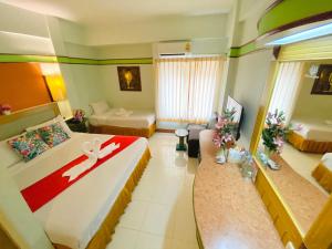 Habitación de hotel con 2 camas y sala de estar. en Polkadot Hostel en Phitsanulok