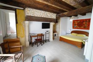 une chambre avec un lit, un bureau et une télévision dans l'établissement LE POTAGER, à Monclard 23 autres photos