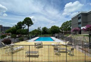 a swimming pool with chairs and a fence at Country Inn & Suites by Radisson, North Little Rock, AR in North Little Rock