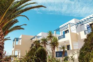 a large white building with palm trees in front of it at Sea Melody in Lefkos Karpathou