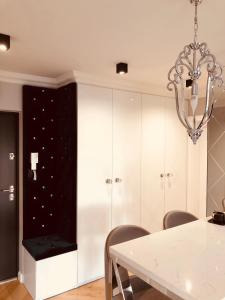 ein Esszimmer mit einem weißen Tisch und einem Kronleuchter in der Unterkunft Apartament Primavera z sauną in Kielce