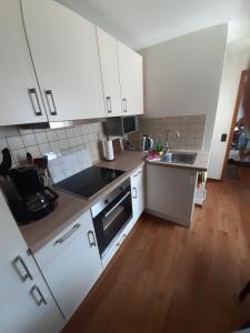 cocina con armarios blancos y suelo de madera en Gästehaus UP-Arnold, en Pinneberg