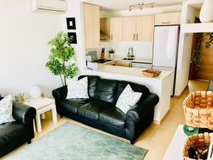 sala de estar con sofá de cuero negro y cocina en 3 Bed Apartment Condado de Alhama Golf Resort, en Alhama de Murcia