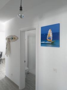 une chambre blanche avec une photo de voilier sur le mur dans l'établissement Apartment Cucharas Beach - Piscina - Beach 2 min. - AC - Wifi, à Costa Teguise