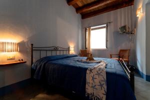 a bedroom with a bed with a blue blanket and a window at Solares Case Vacanze in Ustica