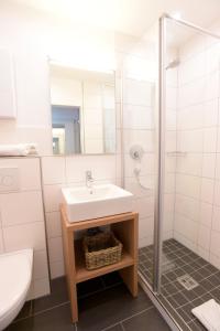 uma casa de banho branca com um lavatório e um chuveiro em Appartement „Klein & Fein“ em Bolsterlang