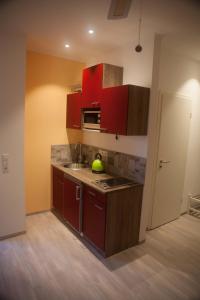 a kitchen with red cabinets and a sink at ApartmentHotel Vollumen in Redwitz an der Rodach
