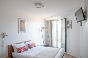 a white bedroom with a bed and a tv at The People - Paris Bercy in Paris