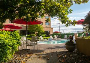 a pool with chairs and umbrellas in front of a building at Monarch Hotel & Conference Center in Clackamas