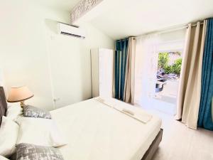 a white bedroom with a bed and a window at SANDY BAY Villa in Ayia Napa