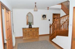 a hallway with a wooden staircase and a mirror at Auburn Cottage in Arbroath