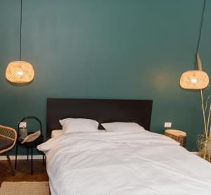 a bedroom with a large bed with white sheets and two lights at ZOR ZON studios in Timişoara