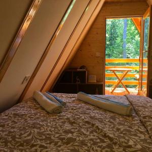 Bett in einem Zimmer mit einem großen Fenster in der Unterkunft Dren Chalet Lux - Banjska stena in Perućac