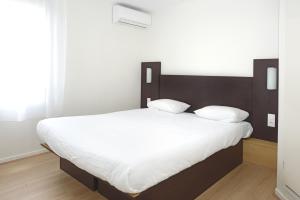 - une chambre avec un grand lit et des draps blancs dans l'établissement Fasthotel Reims-Taissy, à Reims