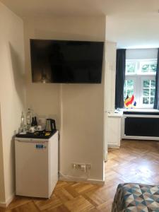 a kitchen with a small refrigerator and a flat screen tv on the wall at Rose House B&B in Ghent