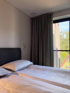 ein Schlafzimmer mit einem Bett und einem großen Fenster in der Unterkunft Apartment KOPA in Pervalka